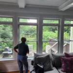 woman looking out of window into a lush backayard